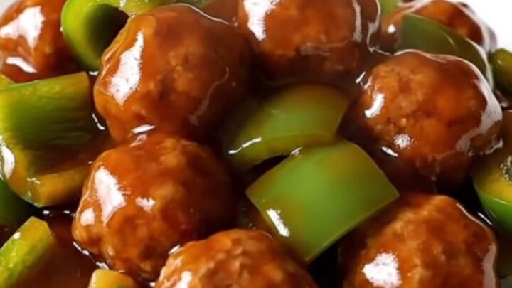 A slow cooker filled with glazed Szechuan meatballs and green bell peppers.