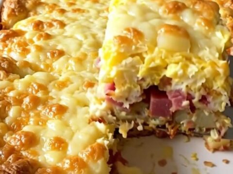 A golden, puffed corned beef hash and egg bake in a white ceramic dish.