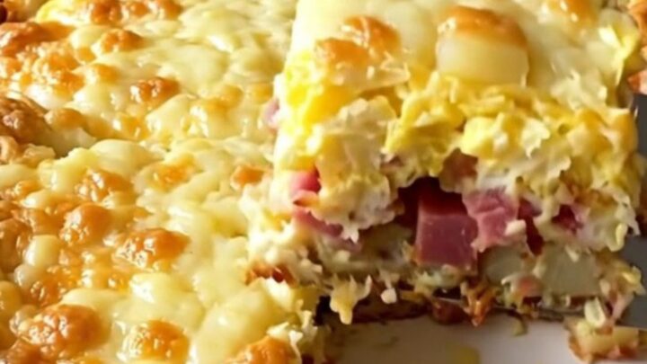 A golden, puffed corned beef hash and egg bake in a white ceramic dish.