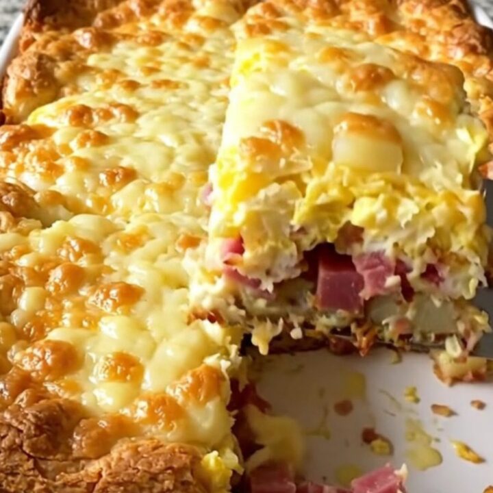 A golden, puffed corned beef hash and egg bake in a white ceramic dish.