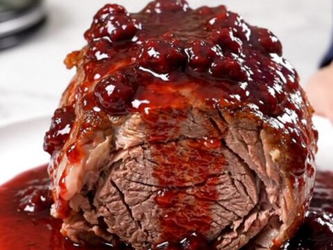 A close-up view of a tender, slow-cooked chuck roast with red onions and a glossy