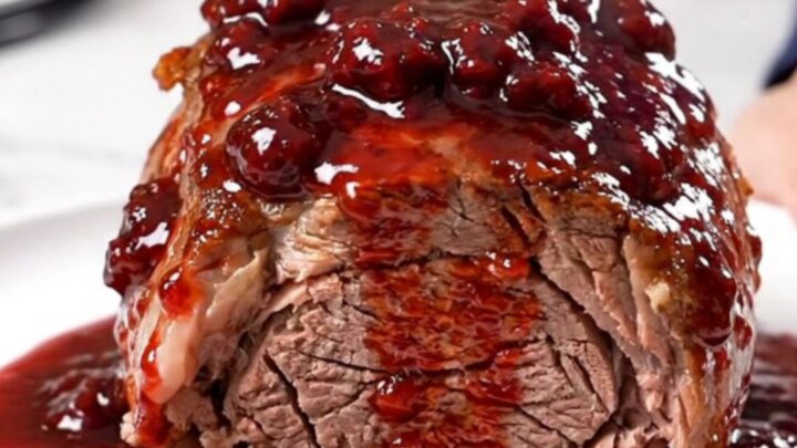 A close-up view of a tender, slow-cooked chuck roast with red onions and a glossy