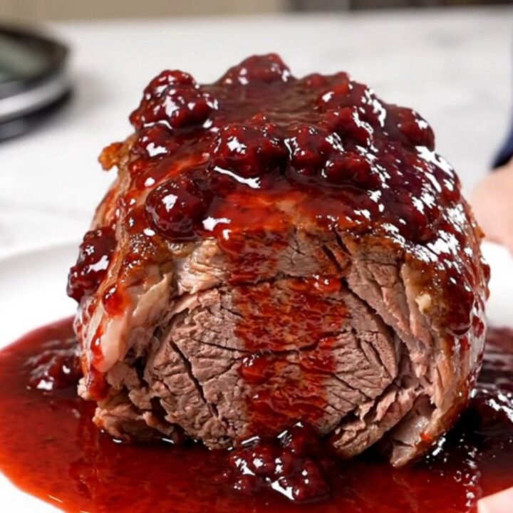 A close-up view of a tender, slow-cooked chuck roast with red onions and a glossy