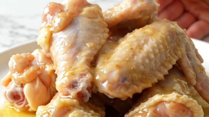 A close-up of garlic parmesan chicken wings served on a white plate, showing the buttery sauce.