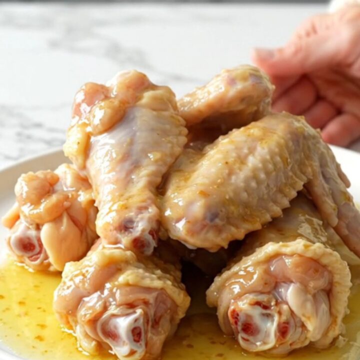 A close-up of garlic parmesan chicken wings served on a white plate, showing the buttery sauce.