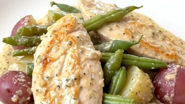 Creamy slow cooker Italian chicken served with green beans and potatoes on a white plate.