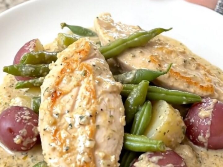 Creamy slow cooker Italian chicken served with green beans and potatoes on a white plate.