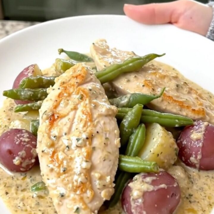 Creamy slow cooker Italian chicken served with green beans and potatoes on a white plate.