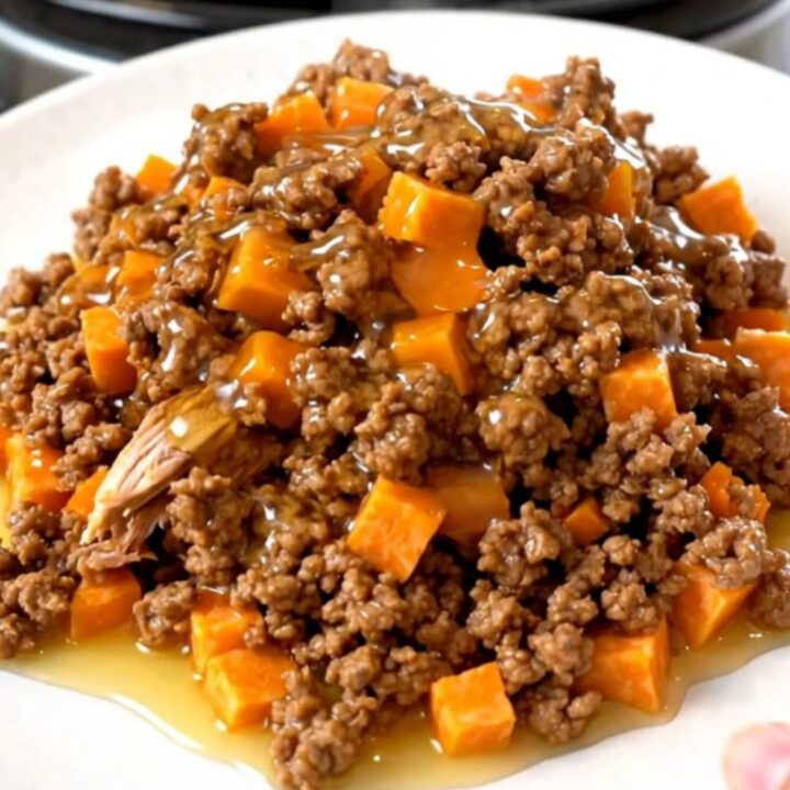 A slow cooker filled with cooked ground turkey and tender sweet potato cubes glazed in a shiny hot honey sauce.