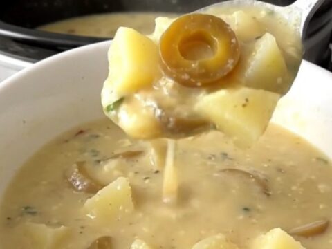 A bowl of creamy Mississippi potato soup with visible pepperoncini rings in a slow cooker setting.