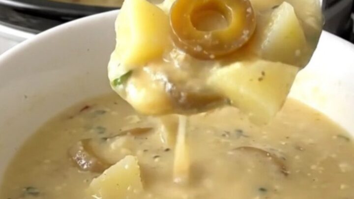 A bowl of creamy Mississippi potato soup with visible pepperoncini rings in a slow cooker setting.