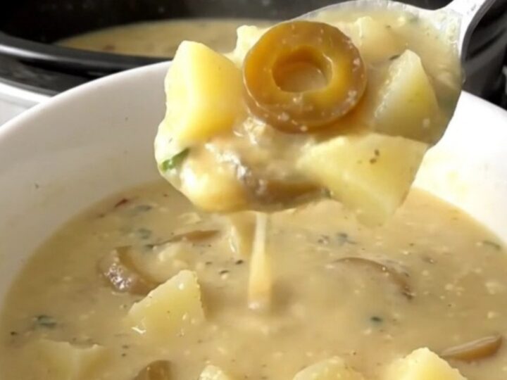 A bowl of creamy Mississippi potato soup with visible pepperoncini rings in a slow cooker setting.