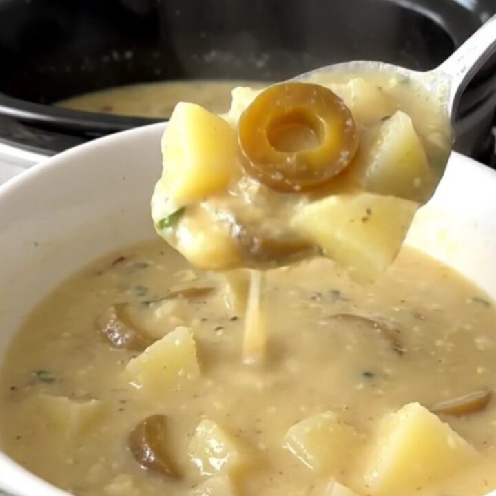 A bowl of creamy Mississippi potato soup with visible pepperoncini rings in a slow cooker setting.