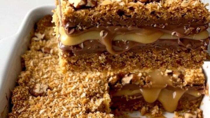 A top-down view of seven layer magic cookie bars in a white ceramic baking dish on a quartz countertop.