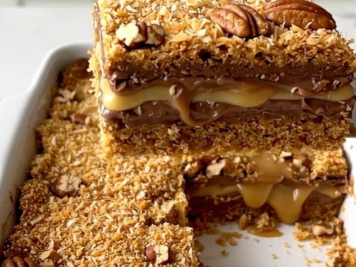 A top-down view of seven layer magic cookie bars in a white ceramic baking dish on a quartz countertop.