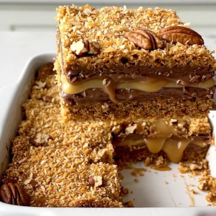 A top-down view of seven layer magic cookie bars in a white ceramic baking dish on a quartz countertop.