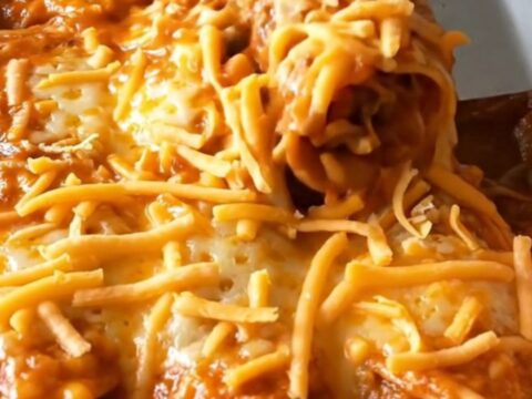 A top-down view of a rectangular baking dish filled with golden-brown, cheese-topped enchiladas.