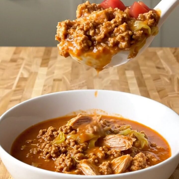 A white ceramic slow cooker filled with a hearty mixture of ground turkey, chopped cabbage, and diced tomatoes.