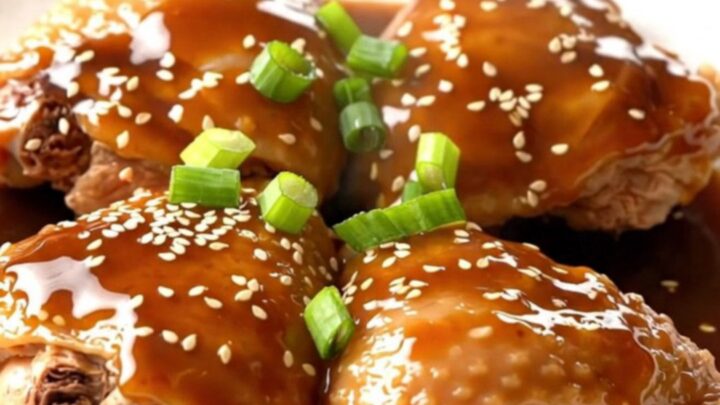 A close-up of tender, braised chicken thighs in a dark, glossy Japanese barbecue sauce