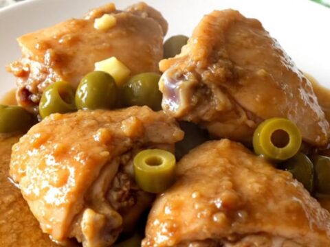 A rustic slow cooker filled with tender chicken thighs, baby red potatoes, and pepperoncini in a rich brown gravy.