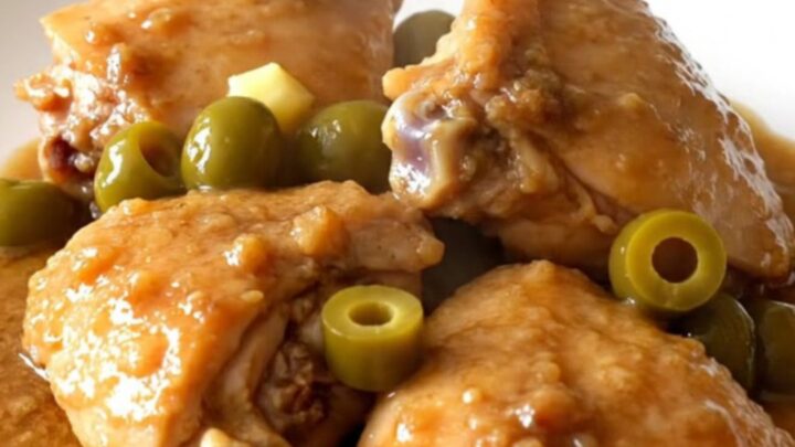 A rustic slow cooker filled with tender chicken thighs, baby red potatoes, and pepperoncini in a rich brown gravy.