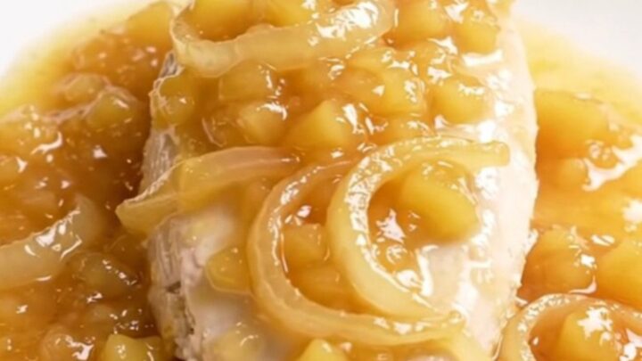 A close-up of slow cooker applesauce chicken on a white plate with visible steam.