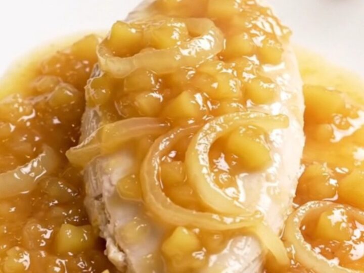 A close-up of slow cooker applesauce chicken on a white plate with visible steam.