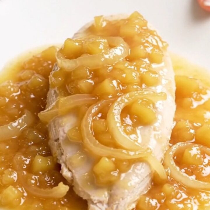 A close-up of slow cooker applesauce chicken on a white plate with visible steam.
