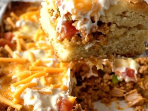 A large rectangular baking dish filled with a golden brown cowboy biscuit casserole on a granite countertop.