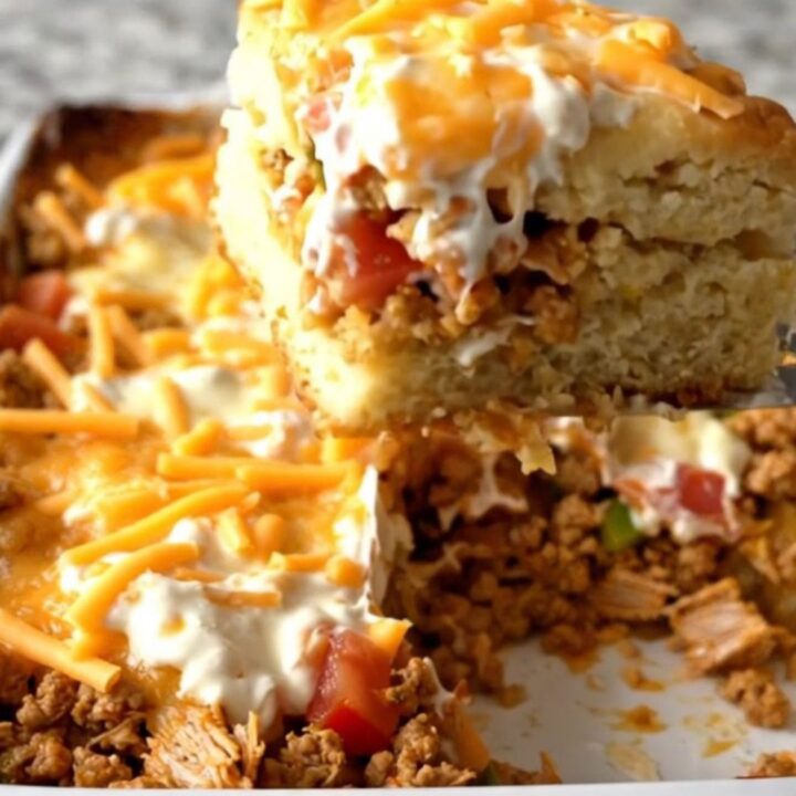 A large rectangular baking dish filled with a golden brown cowboy biscuit casserole on a granite countertop.
