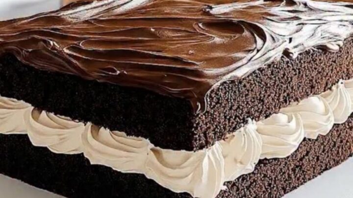 A slice of homemade Ding Dong sheet cake on a white platter, showing distinct layers of chocolate cake and marshmallow cream.