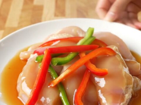 A white plate featuring tender honey pepper chicken strips surrounded by colorful bell pepper slices and a rich