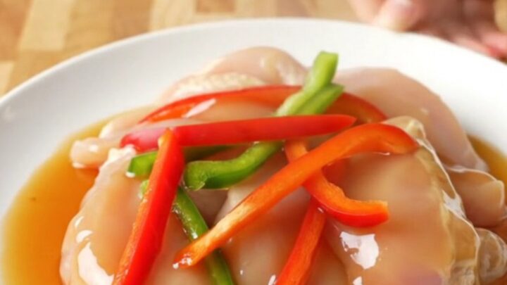A white plate featuring tender honey pepper chicken strips surrounded by colorful bell pepper slices and a rich