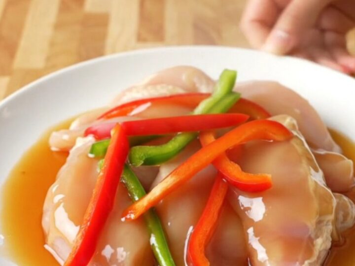 A white plate featuring tender honey pepper chicken strips surrounded by colorful bell pepper slices and a rich