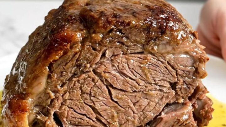 A slow cooker chuck roast served on a white plate with carrots and a rich, buttery lemon sauce.