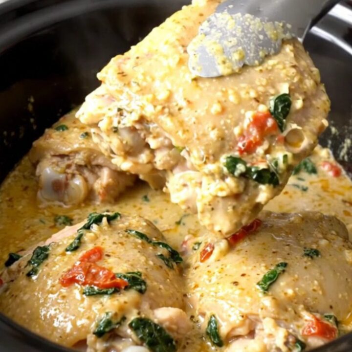 A close-up view of creamy Tuscan garlic chicken thighs served in a white bowl with a rich sauce.