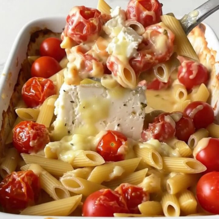 A large ceramic baking dish filled with creamy baked feta and tomato penne.
