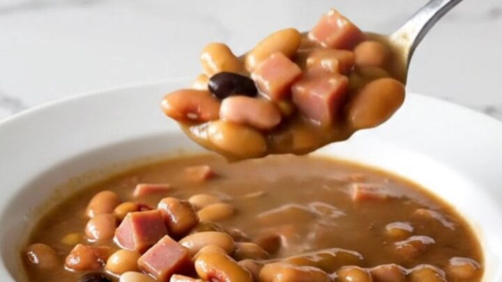 A rustic bowl of fifteen-bean stew with diced ham and a rich brown broth.