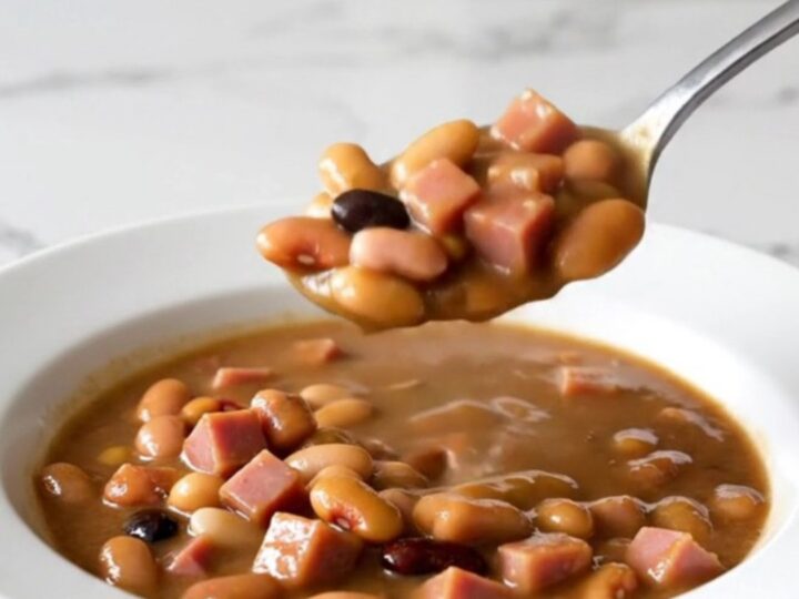 A rustic bowl of fifteen-bean stew with diced ham and a rich brown broth.