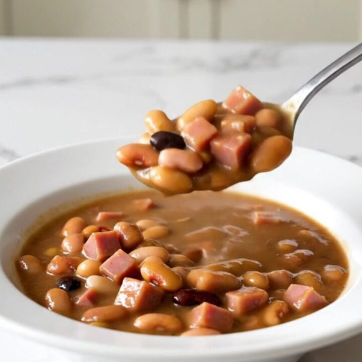 A rustic bowl of fifteen-bean stew with diced ham and a rich brown broth.