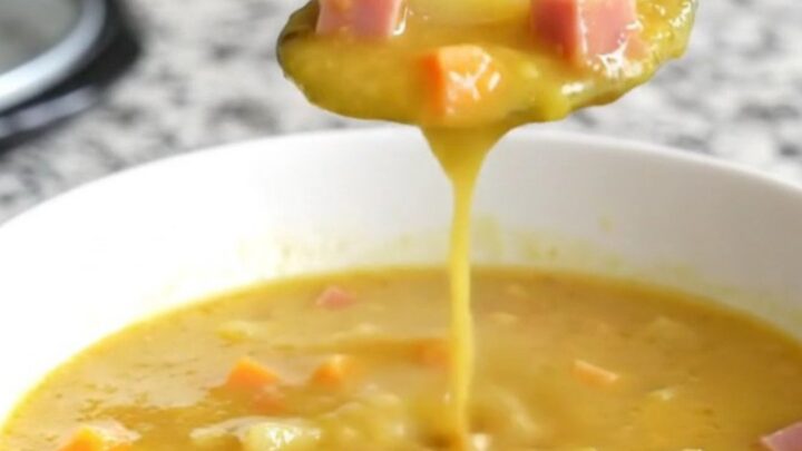 A bowl of creamy beer cheese soup with visible chunks of ham, gold potatoes, and carrots.