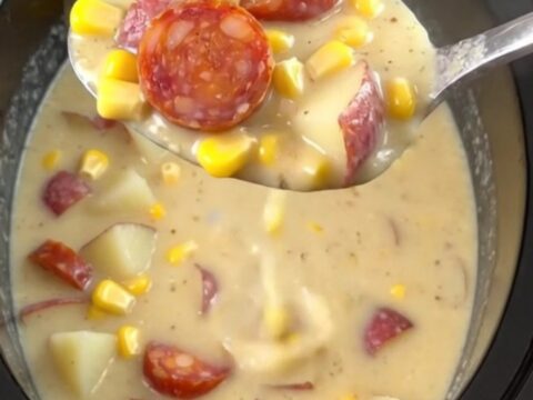 A close-up of a steaming bowl of creamy chorizo corn chowder with visible slices of chorizo and potato cubes.