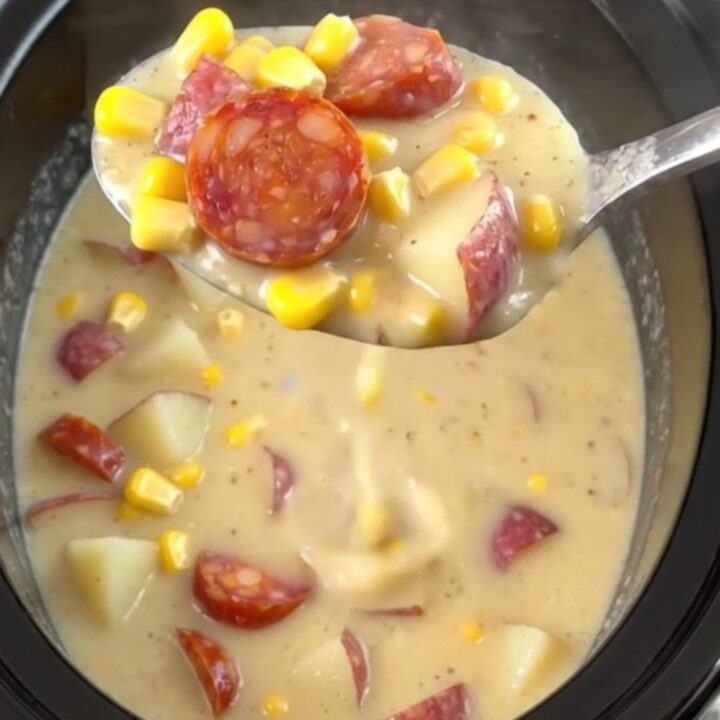 A close-up of a steaming bowl of creamy chorizo corn chowder with visible slices of chorizo and potato cubes.