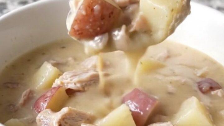 A close-up of a bowl of creamy white cheddar turkey and potato chowder with steam rising.