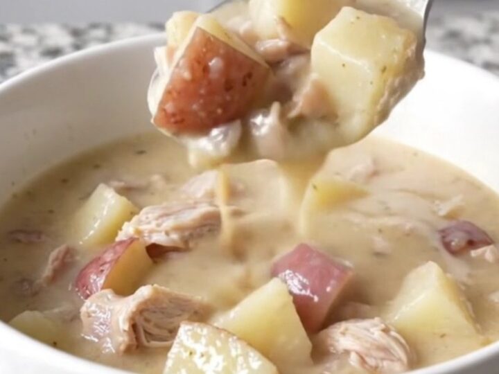 A close-up of a bowl of creamy white cheddar turkey and potato chowder with steam rising.