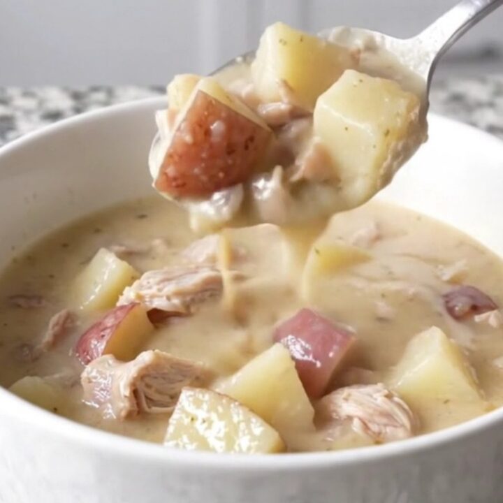 A close-up of a bowl of creamy white cheddar turkey and potato chowder with steam rising.