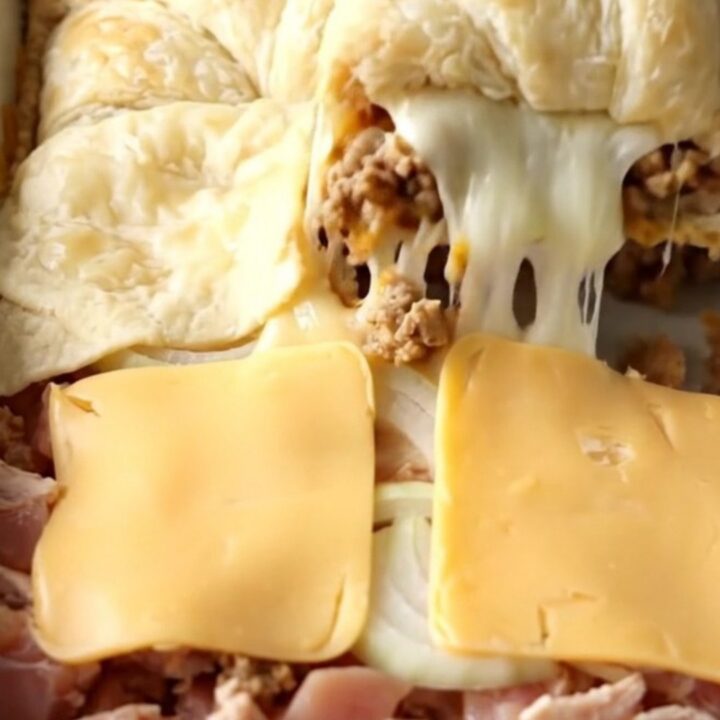 A golden brown crescent roll casserole in a white baking dish on a beige counter.