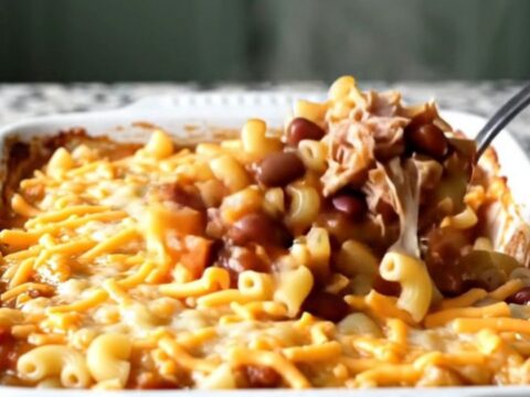 A cheesy, bubbling turkey chili mac bake in a white ceramic dish on a light granite countertop.