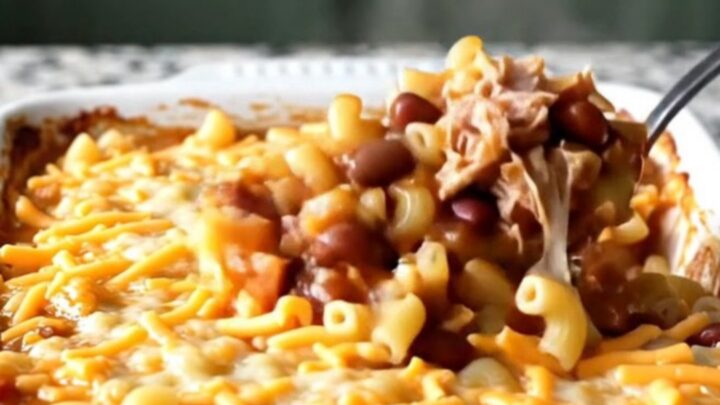 A cheesy, bubbling turkey chili mac bake in a white ceramic dish on a light granite countertop.