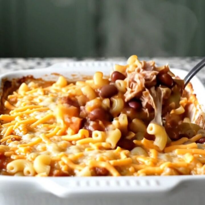 A cheesy, bubbling turkey chili mac bake in a white ceramic dish on a light granite countertop.